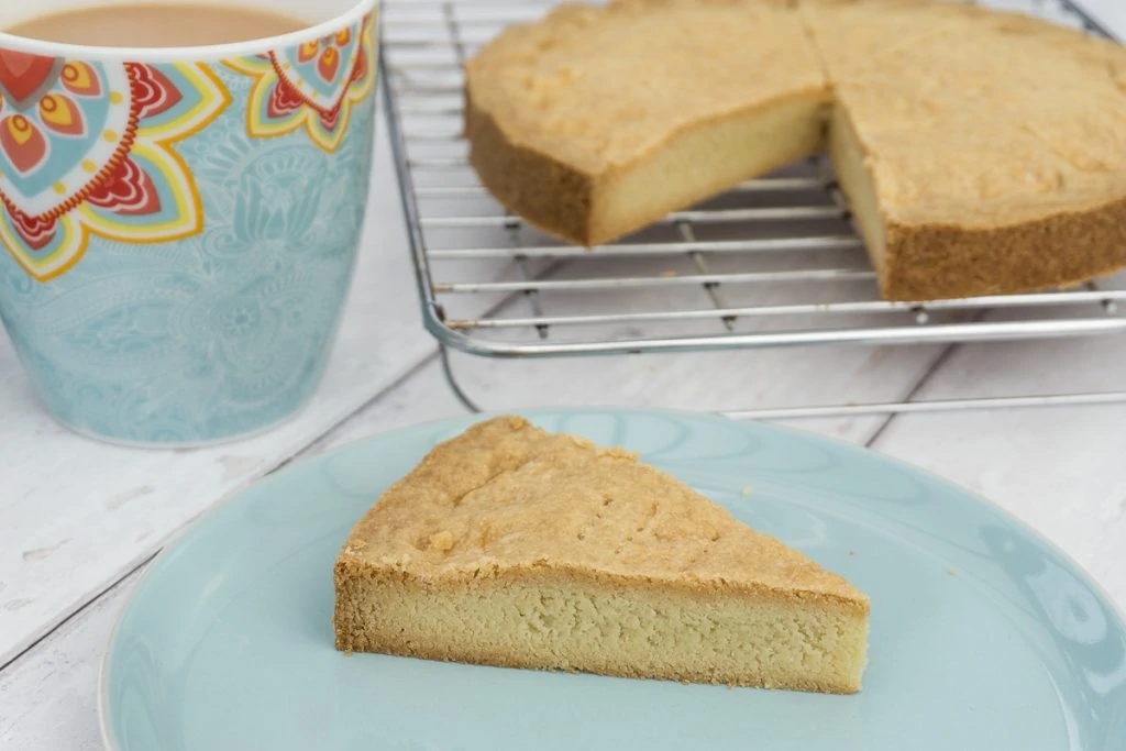 Petticoat Tails Shortbread Recipe cut into pieces and one on a plate with a cup of tea