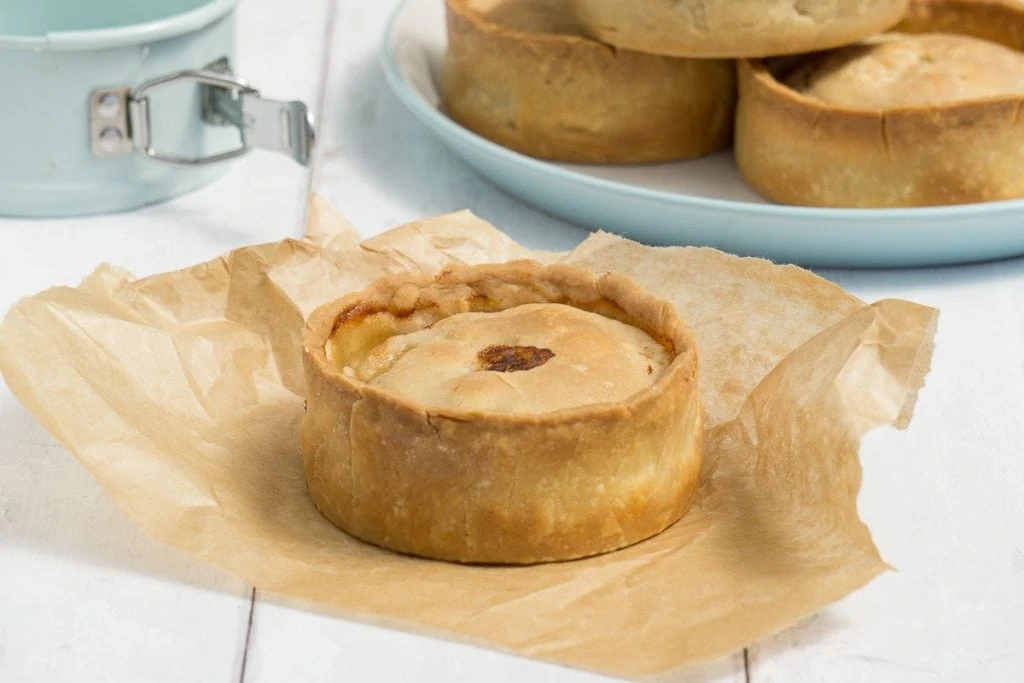 Scotch Pie Recipe - Scotch pie on baking paper with other Scotch pies and tin in background