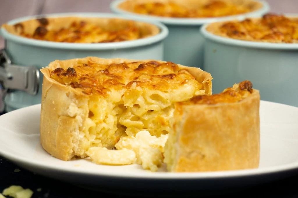Macaroni Scotch Pie Recipe with pie on plate and tins in background
