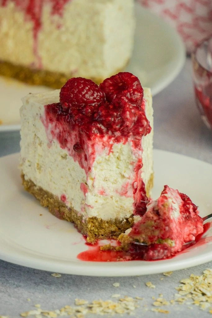 Slice of Scottish Cranachan Cheesecake recipe with raspberries on top and a piece on a fork