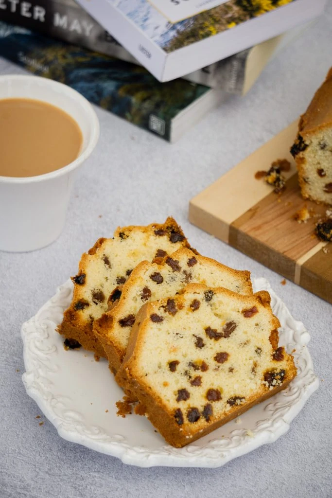 Sultana Loaf Cake on a plate with cup of tea and books
