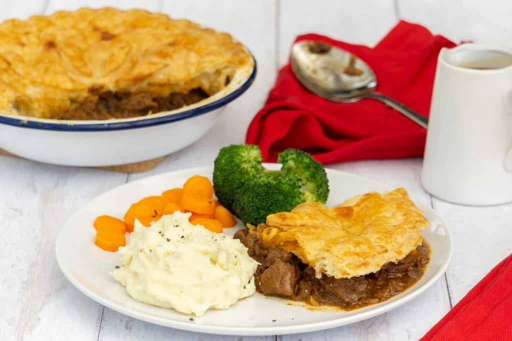 Scottish Steak Pie Recipe in pie dish and on plate with vegetables
