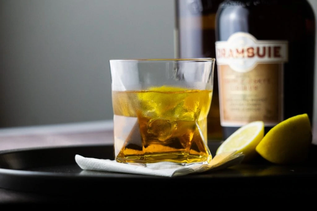 A Rusty Nail cocktail and bottle of Drambuie