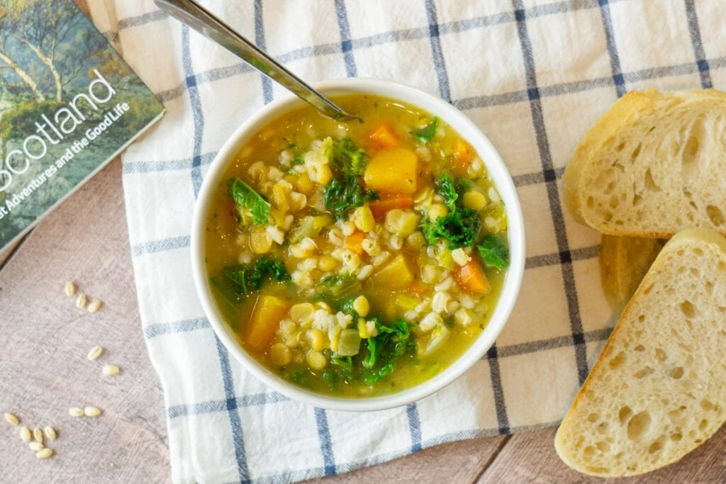 Vegetarian Scotch Broth in a bowl with bread and a book