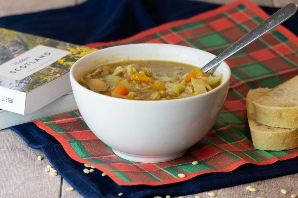 Scotch Broth Recipe in a bowl with bread and books nearby
