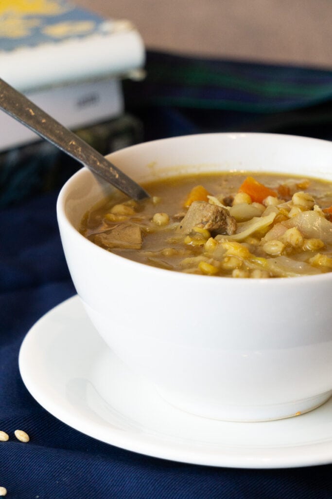 Scotch Broth Recipe in a bowl with bread and books nearby