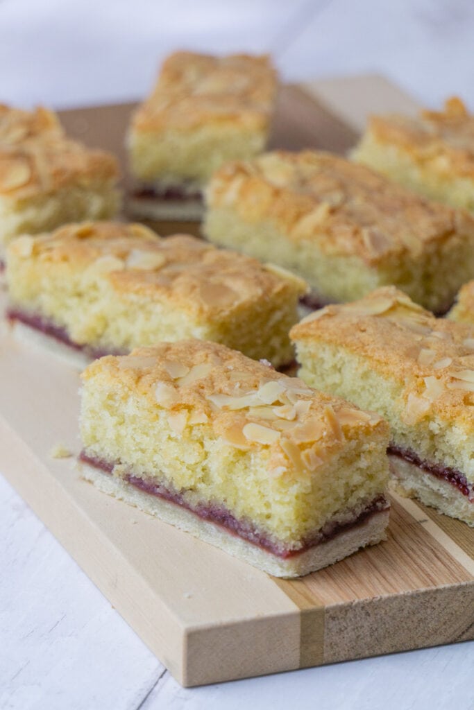 Almond Slice Recipe on a wooden board - A Bakewell Slice with pastry bottom, raspberry jam, and an almond sponge