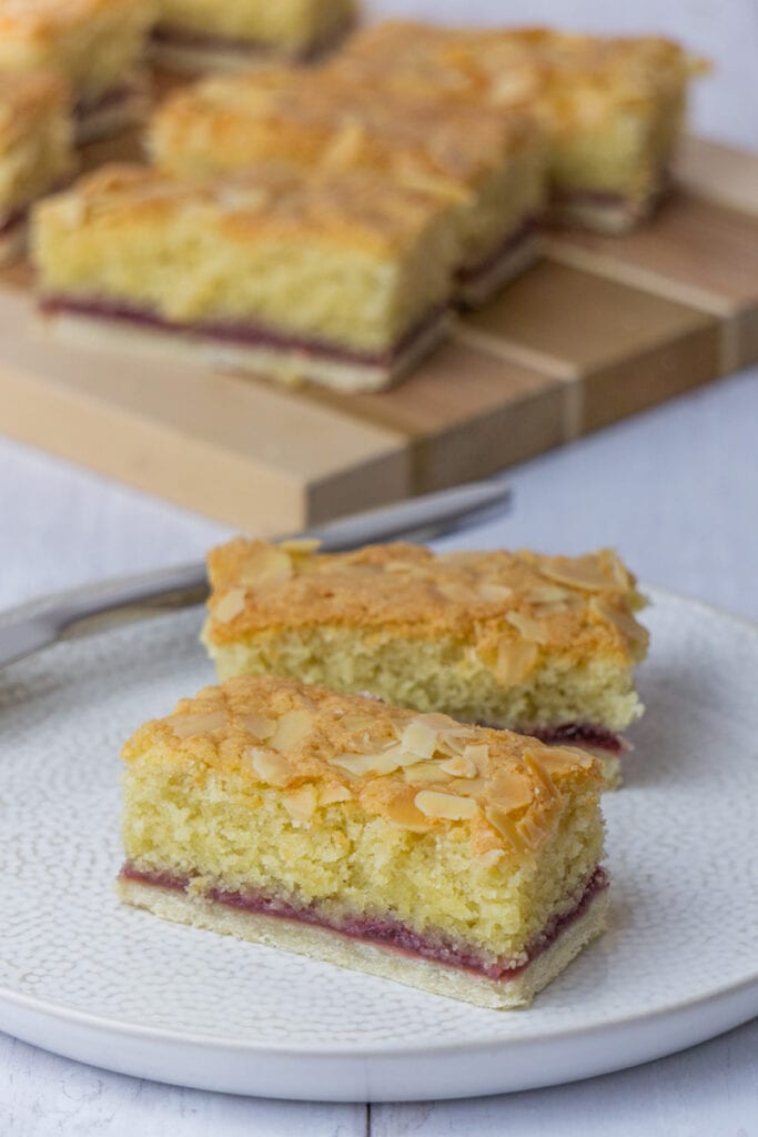 Almond Slice Recipe on a wooden board - A Bakewell Slice with pastry bottom, raspberry jam, and an almond sponge