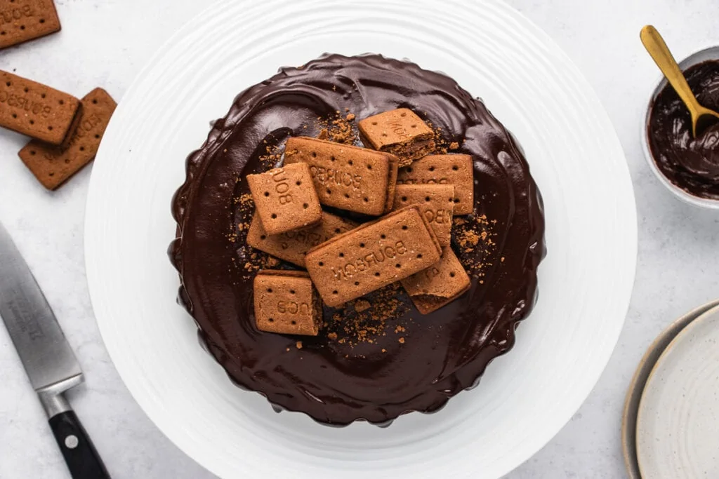 4 Ingredient Bourbon Biscuit Cake Recipe on a plate to down shot with knife, biscuits, and extra ganache in a bowl