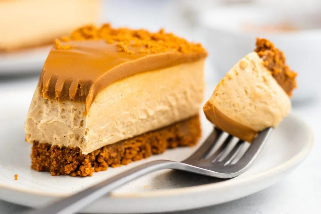 Lotus Biscoff Cheesecake Recipe - Slice on a plate with a fork with small piece on it