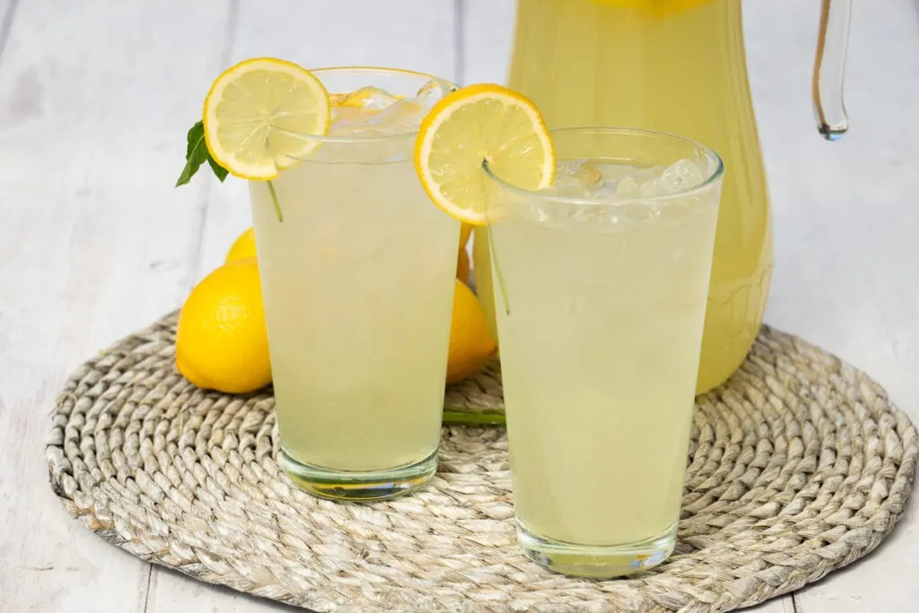 Homemade Lemon Cordial Recipe - two glasses of lemon cordial mixed with water and ice with a slice of lemon